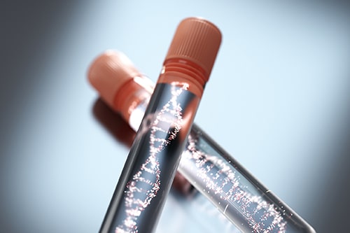 Stock photo of two vials with orange caps filled with a sparkling DNA helix